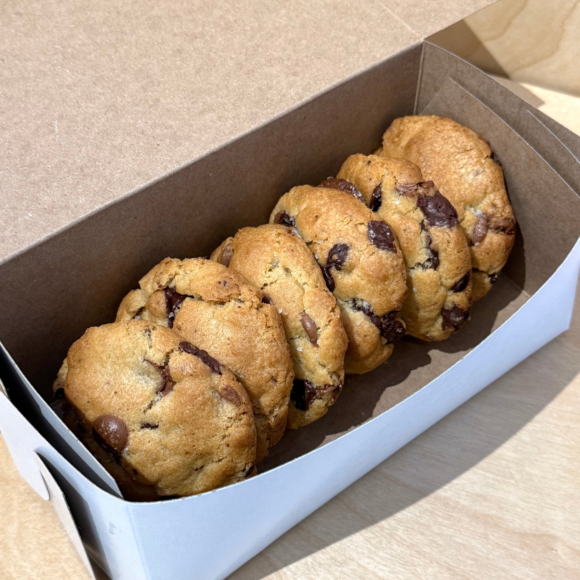 Box of chocolate chip cookies on a light wooden surface