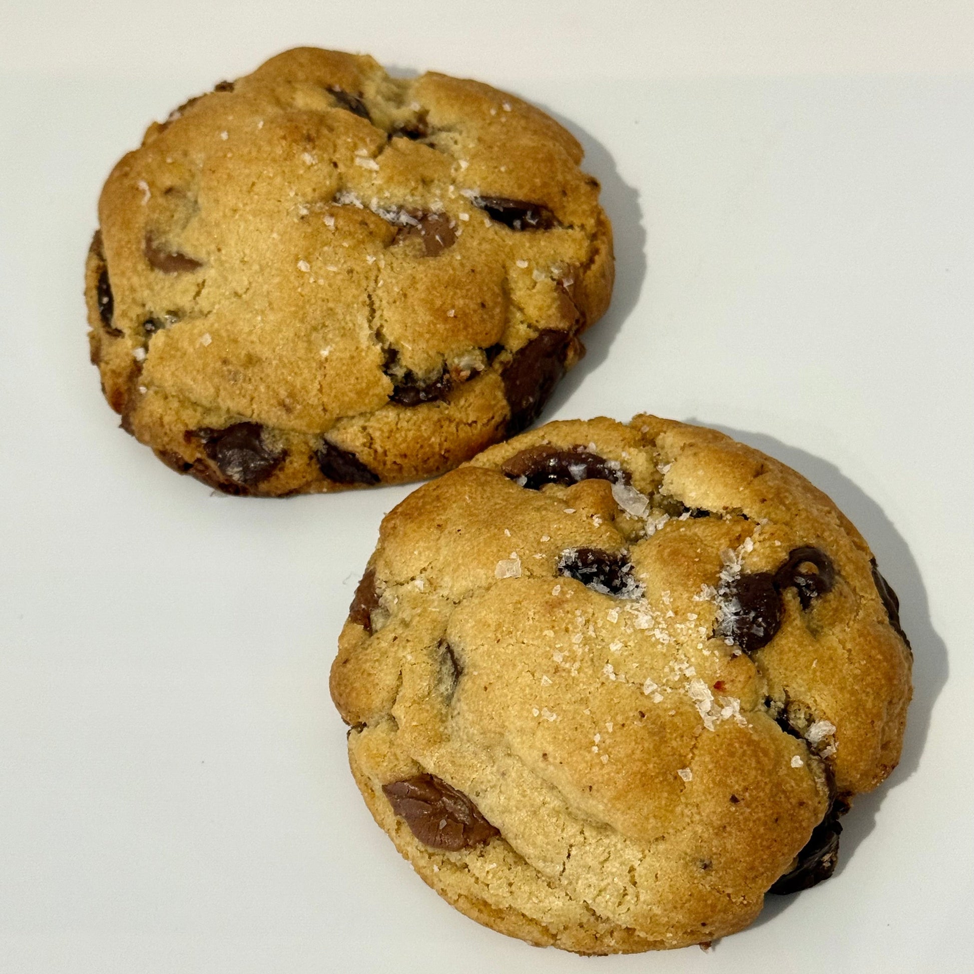 Two chocolate chip cookies on a white surface
